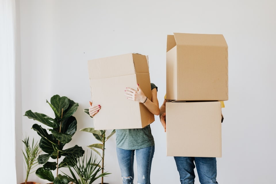couple holding two moving boxes