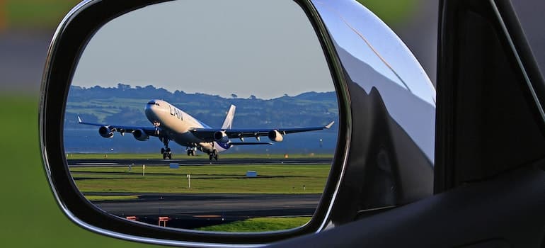 White Airplane Reflection on Car Side Mirror - International moving trends for 2023 