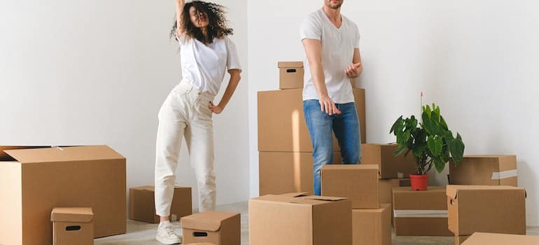 Joyful young couple dancing after moving in new purchased apartment