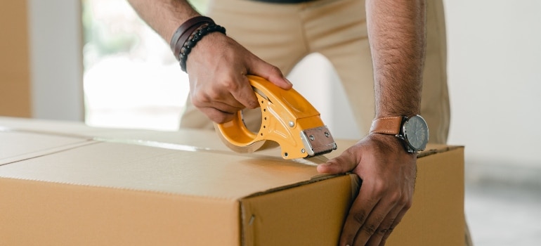 man taping box after getting moving supplies California movers offer