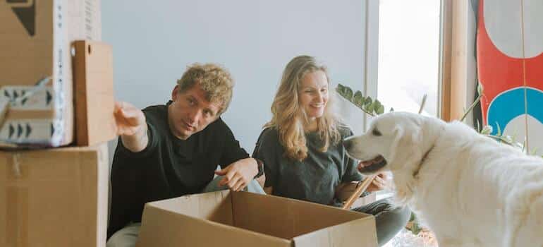 A couple unpacking boxes with their dog around