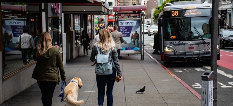 Picture of two women and a dog on a sidewalk 