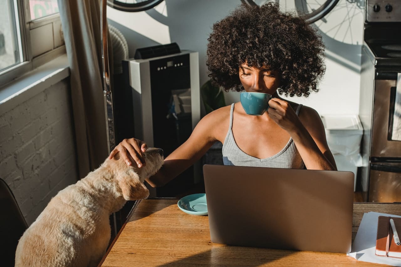 Picture of a woman reading a guide to moving to LA while drinking coffee and petting her dog