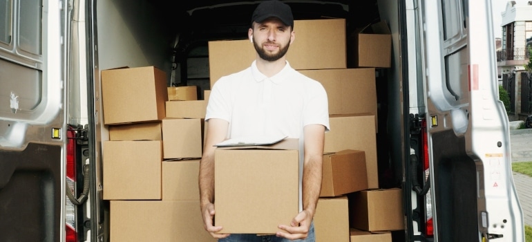 professional mover holding a box in front of the loaded van